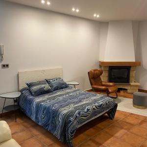 巴基奥Bakio Beach House的一间卧室配有一张床、一把椅子和一个壁炉