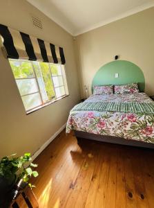 开普敦Rondebosch Cottage的一间卧室配有一张带绿色床头板的床和两个窗户