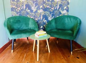 开普敦Rondebosch Cottage的两张绿色椅子坐在桌子旁,书