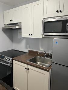 Eastern PassageEast End Suite的厨房配有白色橱柜、水槽和微波炉