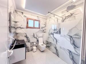泰斯Logu i Harushave的浴室拥有白色和灰色的大理石墙壁和卫生间。