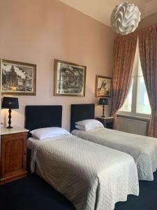 利物浦西庭网球俱乐部酒店的一间卧室配有两张床和吊灯。