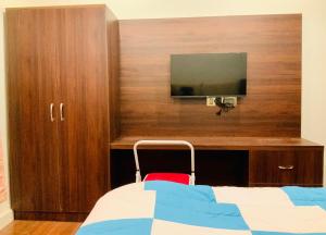 甘托克RIGS Homestay的一间卧室设有一张床,木墙上配有电视。