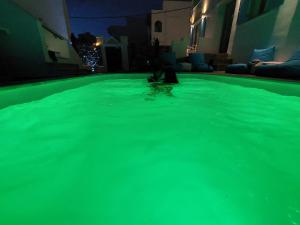 提诺斯TINOS AQUA PALAZZO的游泳池里的人,带绿色照明