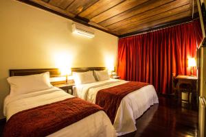 欧鲁普雷图普萨达阿尔坎若酒店的配有红色窗帘的酒店客房的两张床