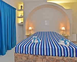 提诺斯TINOS AQUA PALAZZO的一间卧室配有一张蓝色和白色条纹的床