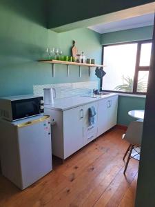 开普敦Rondebosch Cottage的厨房配有白色家电、桌子和窗户