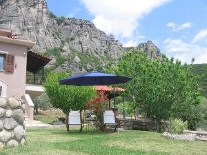 卡兰巴卡Meteora Olio Hills apartment的山前的桌椅和遮阳伞