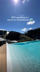 布克维SAVOIE Apartments Bukovel的蓝色的游泳池,阳光在天空中