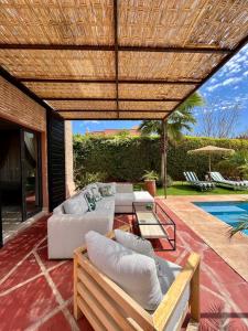 马拉喀什Villa Sofia - Golf Amelkis Marrakech的带沙发和桌子的庭院以及游泳池。