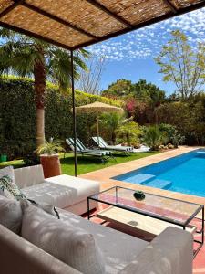 马拉喀什Villa Sofia - Golf Amelkis Marrakech的带沙发和游泳池的客厅