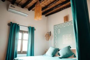 RissaniDar Haroun的一间卧室配有一张带蓝色窗帘的床和一扇窗户