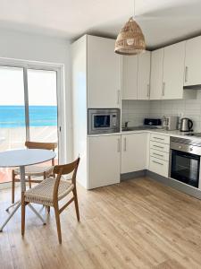 阿尔布费拉罗西奥海公寓式酒店的厨房配有白色橱柜、桌子和桌椅