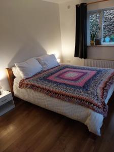 KilteganFelicity Cottage的一间卧室配有一张带彩色毯子的床