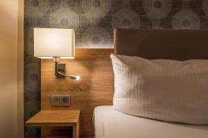 柏林阿尔特市场酒店的一间卧室配有一张带台灯和边桌的床