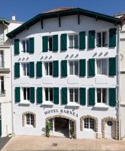 比亚里茨Hôtel Barnea的白色的建筑,设有绿色百叶窗