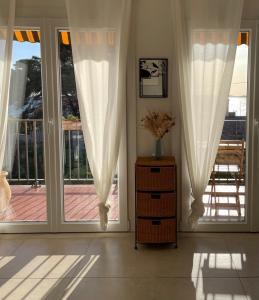 勒普拉代Appartement cosy vue mer à 50 m de la plage - refait à neuf et climatisé的客房设有2扇带白色窗帘的大窗户