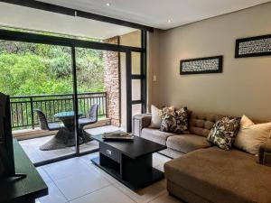 巴利托Resort Retreat, Private Suite, Zimbali Estate的带沙发和桌子的客厅以及阳台。