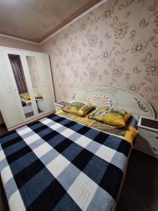 巴甫洛达尔Назарбаева 204的一间卧室配有一张带蓝白色毯子的床