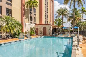 迈阿密迈阿​​密机场西汉普顿酒店的一座带椅子和棕榈树的游泳池以及建筑