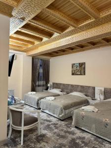 撒马尔罕阿尔巴酒店的一间设有三张床的房间,内设一张桌子