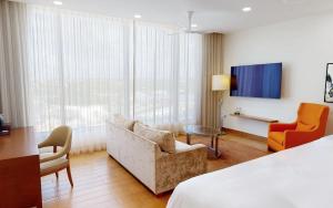 Rendezvous BeachAurora Anguilla Resort & Golf Club的酒店客房配有一张床、一张沙发和椅子。