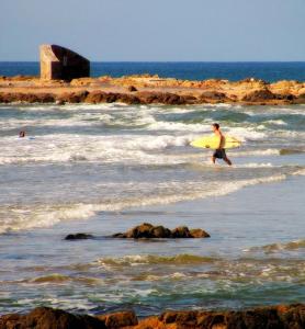 埃斯特角城ZAG Coliving Punta del este的带着黄色冲浪板走进大海的人