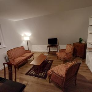 万泽内姆Les vignobles d'Alsace的客厅配有椅子、桌子和电视