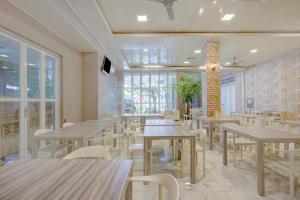 雅加达Super OYO 4005 Bunga Dahlia Guest House的配有木桌和白色椅子的餐厅