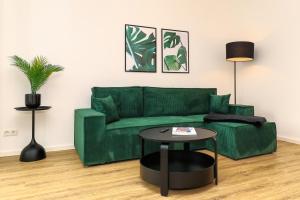 布伦瑞克LIGHTPLACE - Moderne Apartments in Braunschweig - Balkon - Netflix - Am Kanal的客厅配有绿色沙发和桌子