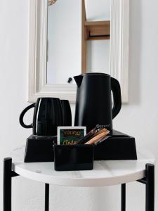 毕达哥利翁Blue Sardines的一张桌子,上面有黑咖啡壶和一个盒子