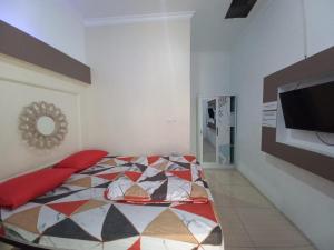 PundongOYO 93962 Jm Guest House的一间卧室配有一张床和一台平面电视