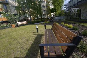 普瓦维Czartoryskich 7 - parking w cenie -的坐在建筑物旁边的草地上的公园长凳