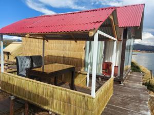 普诺Coila Titicaca lodge的一座红色屋顶的房子,甲板上设有一张桌子