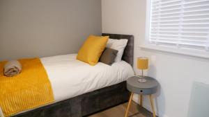 北安普敦Stylish 2 bedroom Apartment in Kettering Town Centre, sleeps 4, free parking, wifi, Sky, Netflix的一间卧室配有一张带黄色枕头的床和一扇窗户