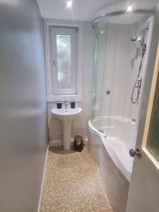 爱丁堡Spacious 3 bed with free parking的浴室配有水槽、淋浴、浴缸和水槽。