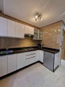 纳祖尔Hotel Residence Ramsis的厨房配有白色橱柜和黑色台面