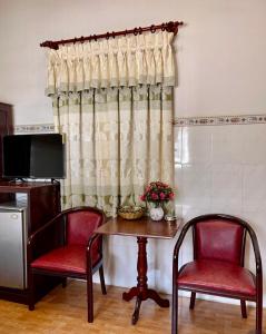 芹苴Khách sạn Nam Đô 2的配有桌子、两把椅子和窗帘的房间