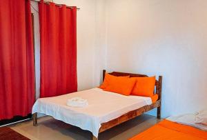 卢纳将军城RedDoorz @ Hergem Siargao Inn的一间卧室配有带橙色枕头和红色窗帘的床