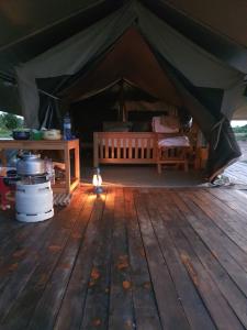 Kisarukabwoya Safari camp Kaiso village的大型帐篷铺有木地板,配有桌子