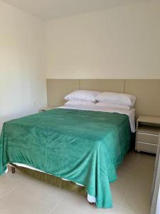 马塔迪圣若昂Praia do Forte - COND ALTO DA ENSEADA - Casa 302的一间卧室配有一张带绿毯的床