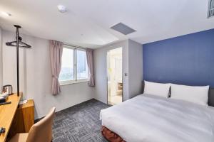 台中市Hotel Leisure 台中輕行旅的一间卧室配有一张床、一张书桌和一个窗户。