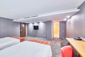 台中市Hotel Leisure 台中輕行旅的酒店客房设有两张床、一张桌子和一台电视。