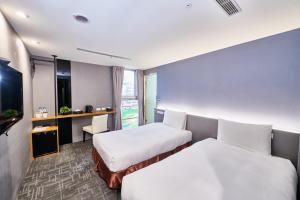 台中市Hotel Leisure 台中輕行旅的酒店客房设有两张床和电视。