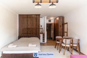 科帕奥尼克Sunčana Planina - Apartmani Wombat的卧室配有一张床和一张桌子及椅子