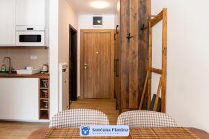科帕奥尼克Sunčana Planina - Apartmani Wombat的厨房设有木门和两把椅子