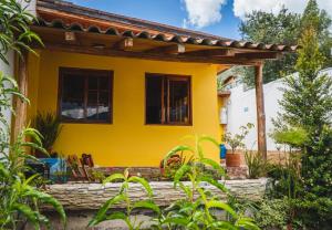 奥塔瓦洛Hospedaje Cabaña Familiar的黄色的房屋,设有木制凉棚