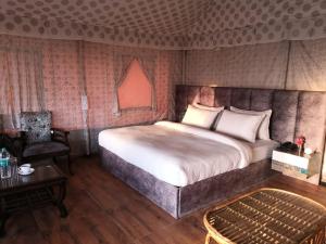 萨哈兰普尔Pulastya Wellness Resort的卧室配有1张床、1张桌子和1把椅子