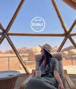 瓦迪拉姆Wadi rum Bubble luxury camp的坐在椅子上喝杯咖啡的女人