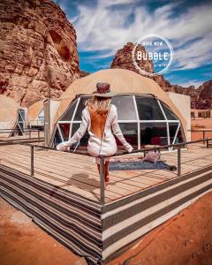 瓦迪拉姆Wadi rum Bubble luxury camp的站在帐篷前的木板路上的女人